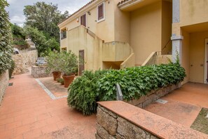 Un bâtiment avec un chemin en pierre, des plantes en pot et un escalier menant à un étage supérieur.