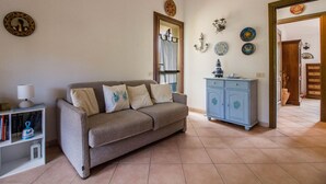 A living room with a sofa, a cabinet, and a bookshelf. - GuestHost - Cozy 55 sqm apartment, ideal for 3 people, located on the first floor of a building without a lift.The property is located in San Pantaleo, a charming village in the hinterland of the Costa Smeralda, which combines the authentic charm of loca (San Pantaleo)