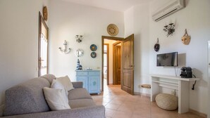 A living room with a sofa, a TV, a small table, and a cabinet. - GuestHost - Cozy 55 sqm apartment, ideal for 3 people, located on the first floor of a building without a lift.The property is located in San Pantaleo, a charming village in the hinterland of the Costa Smeralda, which combines the authentic charm of loca (San Pantaleo)