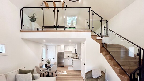Amplia sala de estar con entrepiso, cocina y escalera.