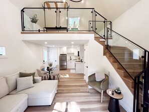 A spacious living area with a loft bedroom, a kitchen, and a staircase. - Carriage House Suite Downtown Stratford (Stratford)