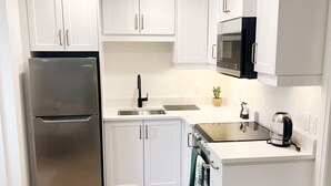 Una cocina moderna con armarios blancos, electrodomésticos de acero inoxidable y piso de madera.