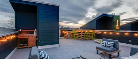 Eine Dachterrasse mit Sitzgelegenheiten im Freien, einer Bar und Lichterketten.