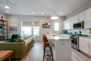 A modern kitchen with white cabinets, a central island, and a built-in microwave. - East Nash Lux - 13 Beds City Views (Nashville)