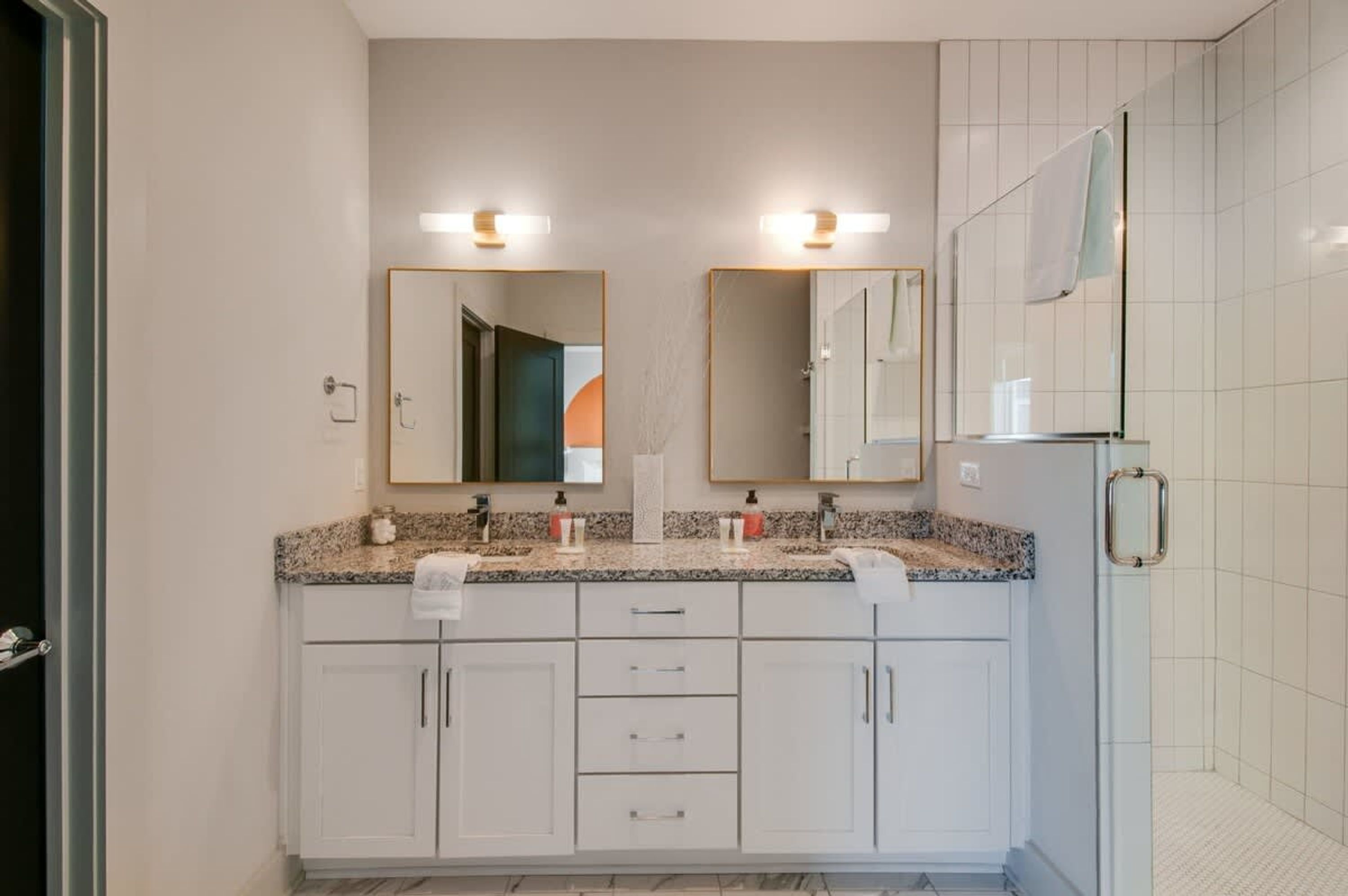 A bathroom with a double sink vanity, a mirror above each sink, and a shower area with a glass door.