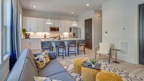 A modern kitchen with white cabinets, a central island with bar stools, and pendant lighting. - East Nash Oasis - 13 Beds - Going Fast (Nashville)