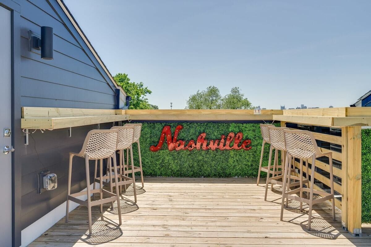 Una terraza de madera con dos sillas de mimbre y un cartel que dice 'Nashville' al fondo.