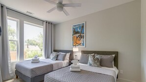A bedroom with two beds, a ceiling fan, and a poster on the wall. - East Nash Oasis - 13 Beds - Going Fast (Nashville)