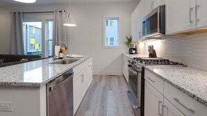 A modern kitchen with granite countertops, stainless steel appliances, and white cabinetry. - East Nash Oasis - 13 Beds - Going Fast (Nashville)