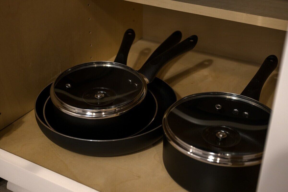 Deux poêles noires avec couvercles, rangées dans un placard.