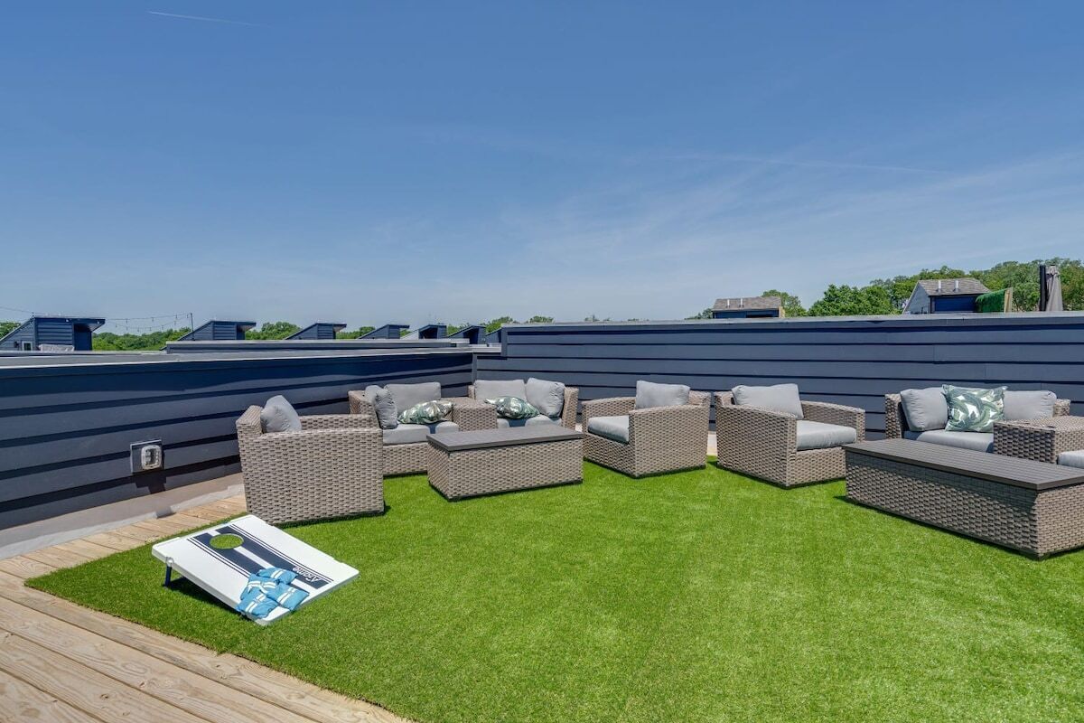 A rooftop patio with wicker furniture and artificial grass.