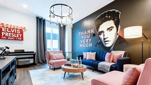 A modern living room with a large mural, a piano, and a cozy seating area.