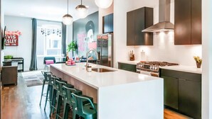 A modern kitchen with a central island, stainless steel appliances, and pendant lighting.