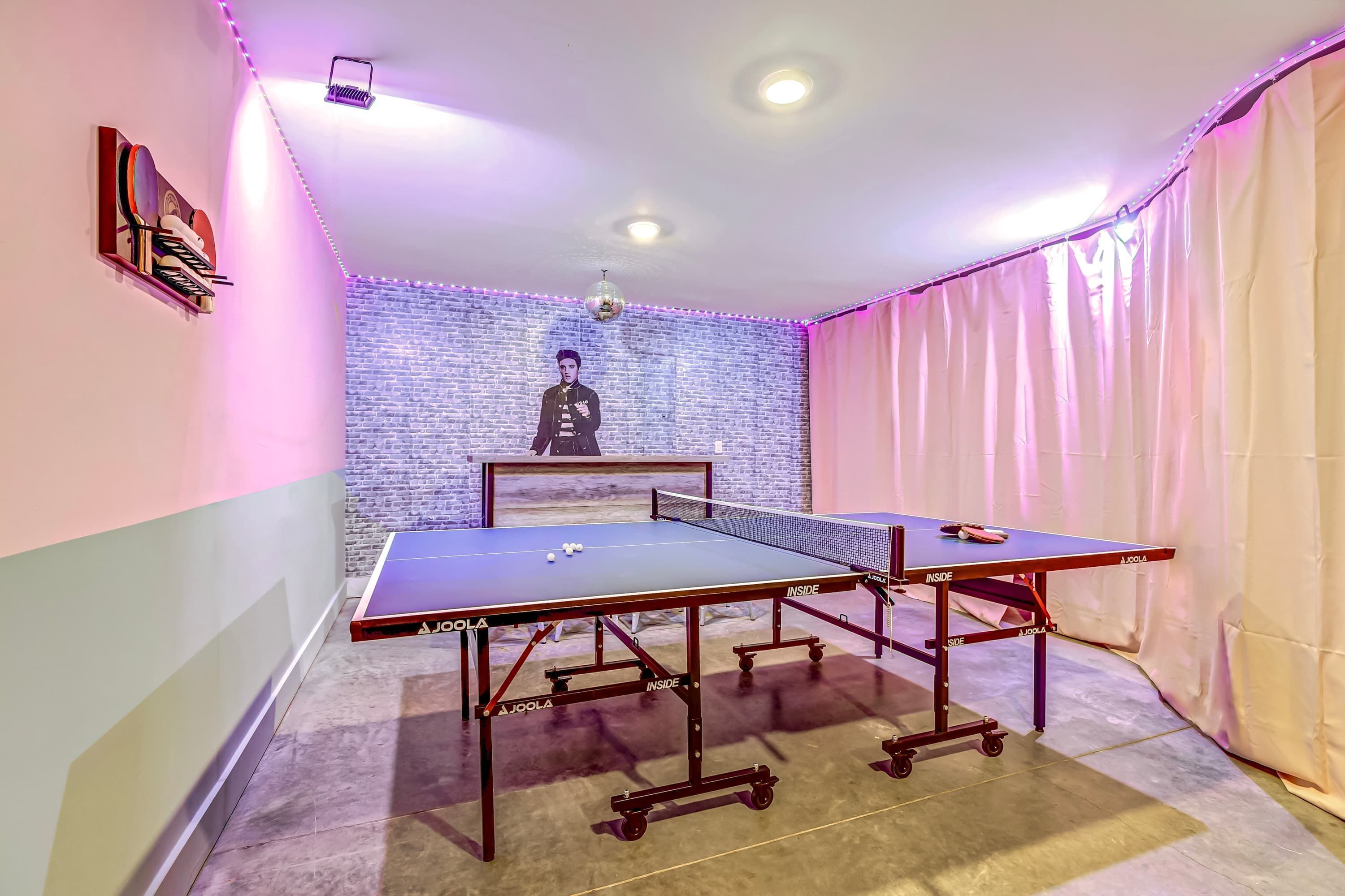 A ping pong table with a net, a brick wall, and a disco ball.