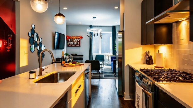 A modern kitchen with a central island, stainless steel appliances, pendant lighting, and a dining area with a view.