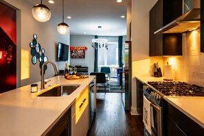 A modern kitchen with a central island, stainless steel appliances, pendant lighting, and a dining area with a view.