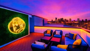 A rooftop terrace with seating and a neon portrait.