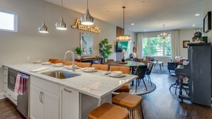 A modern kitchen with a central island, dining area, and a piano.
