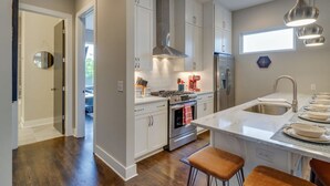 A modern kitchen with white cabinets, stainless steel appliances, and a central island with stools.