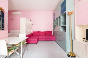 Une pièce décorée dans des tons de rose, avec un bureau blanc, un canapé rose et un grand lampadaire.