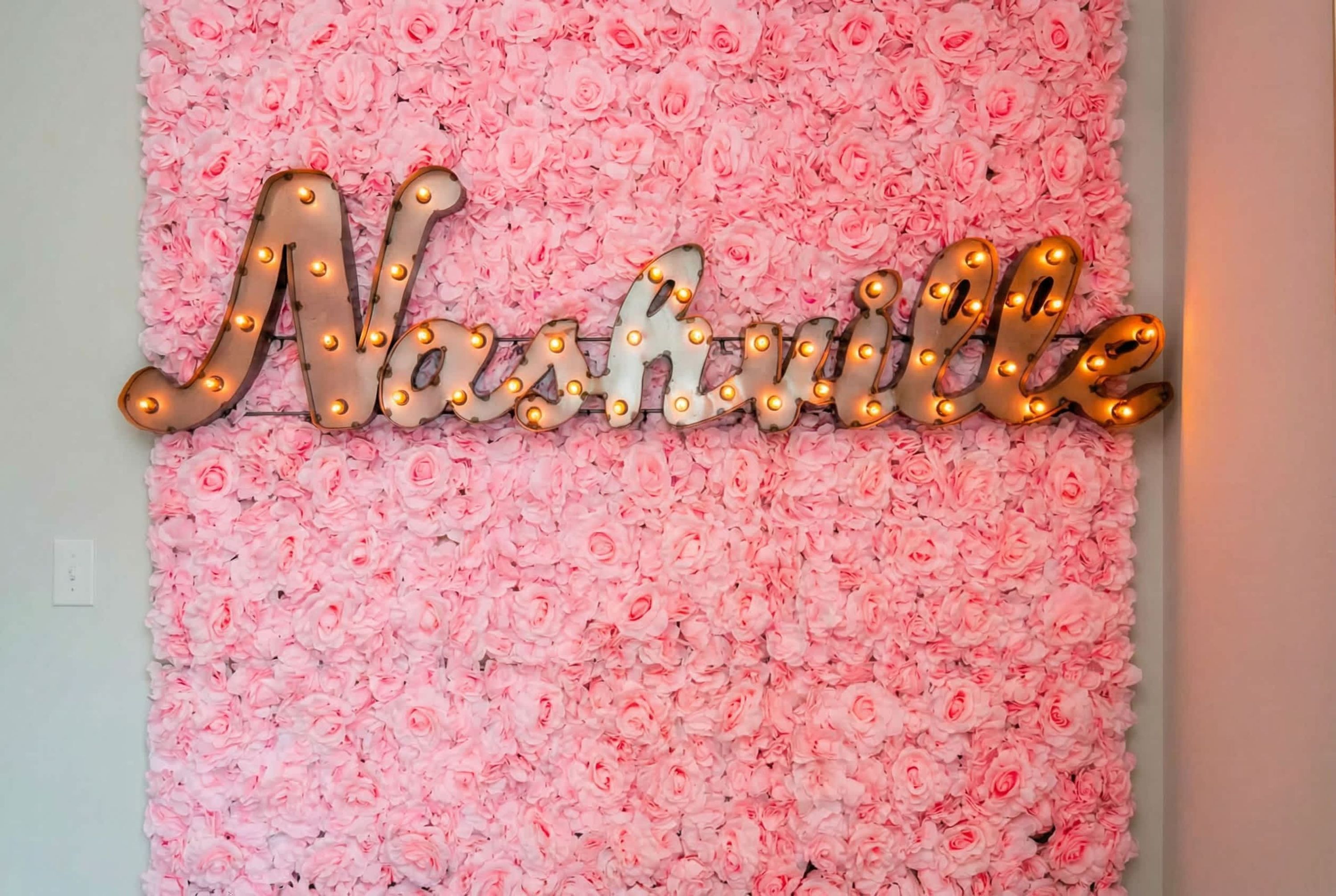 A wall with a floral arrangement and illuminated letters spelling 'Nashville.'