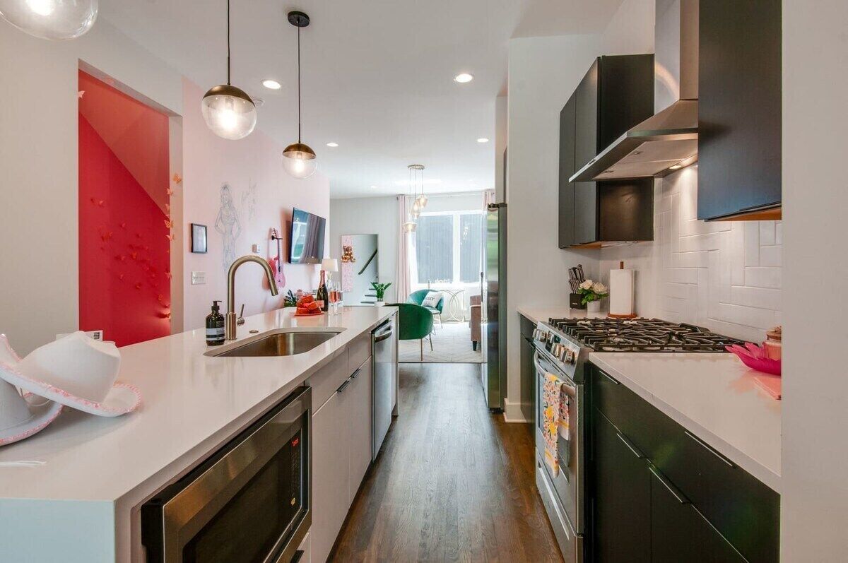A modern kitchen with white countertops, stainless steel appliances, and pendant lighting.