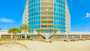 A modern, multi-story hotel with a curved facade, balconies, and a beachside location.