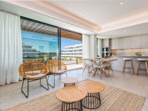 Un intérieur moderne comprenant un coin repas, une cuisine et de grandes fenêtres offrant une vue sur la ville.