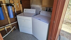 A compact kitchen with a stove, two washing machines, and a water heater.