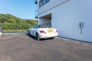 A white convertible car parked in front of a modern building with a clear view of a green hillside in the background. - River View Prime River Front Location (Seaton)