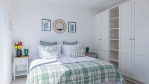 Een slaapkamer met een bed, nachtkastjes, een kledingkast en decoratie aan de wand.