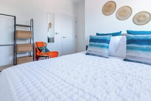 A bedroom with a large bed, a chair, a ladder with baskets, and three woven wall decorations. - River View Prime River Front Location (Seaton)