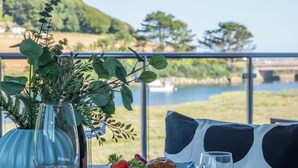 Een eettafel met een schaal aardbeien, een gebakje en een glas water, met op de achtergrond een mooi uitzicht op een rivier en heuvels.