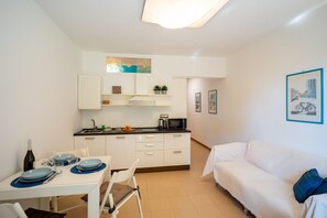 Un espacio habitable compacto con comedor, kitchenette y sofá.