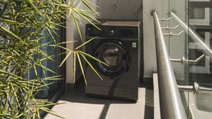 A balcony with a washing machine, a metal railing, and a bamboo plant. - Studio apartment in Nairobi, close to JKIA airport and SGR, WiFi, pool & gym (Nairobi)