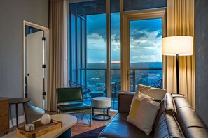 A modern hotel room with a large window, a sofa, a chair, a lamp, and a small table with a tray. - Del Rio - Rooftop pool & Rainey St balcony (Austin)