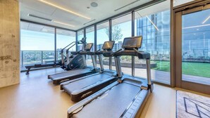 Une salle de sport moderne équipée de tapis de course, de vélos elliptiques et d’un banc de musculation.