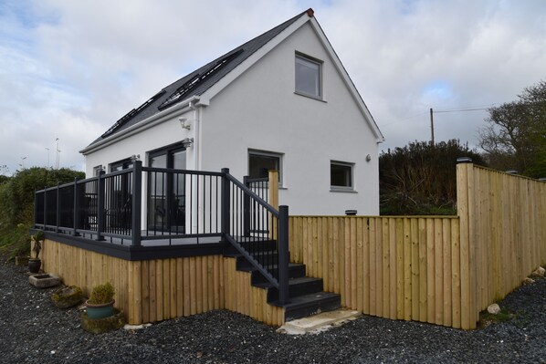 A modern two-story house with a wooden deck and black railings.