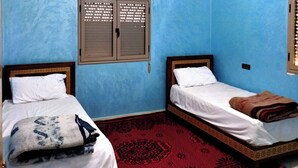 Une chambre avec deux lits, un tapis rouge à motifs et un luminaire fixé au plafond.