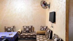 Une pièce comprenant un canapé, un téléviseur fixé au mur et un ventilateur de plafond.