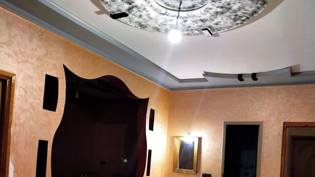 Une pièce spacieuse dotée d’un grand miroir, d’un lavabo et d’un plafond au design original.