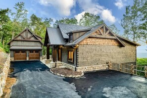 Eine zweistöckige Blockhütte mit einem steilen Satteldach, einem Steinfundament und einer Garage mit Holztüren.