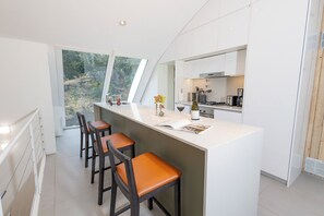 A modern kitchen with a central island, bar stools, and a view of the outdoors. - B612 Bariloche (San Carlos de Bariloche)