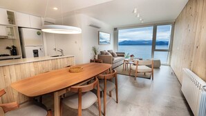 A modern kitchen with a wooden table and chairs, a dining area with a view of the sea, and a cozy living space with a sofa and a coffee table. - B612 Bariloche (San Carlos de Bariloche)