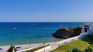 A coastal view with a clear blue sea, boats, and a rocky cliff. - Studio apartment with stunning sea views in the heart of the city (Albufeira)