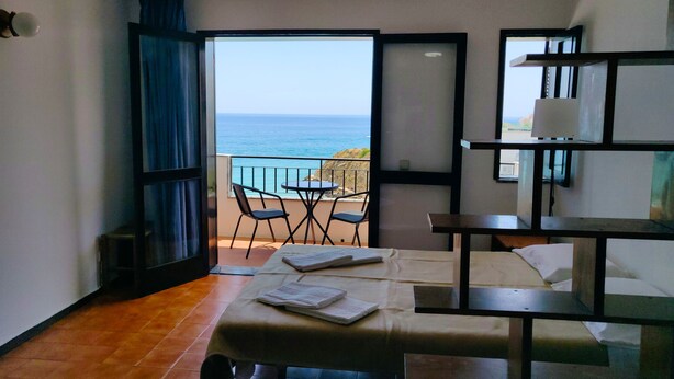 A room with a bed, a small table, and a chair. There is a balcony with a view of the sea. - Studio apartment with stunning sea views in the heart of the city (Albufeira)