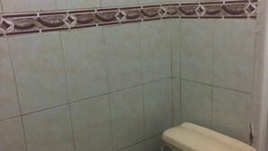 A small bathroom with a toilet, tiled walls, and a decorative border.
