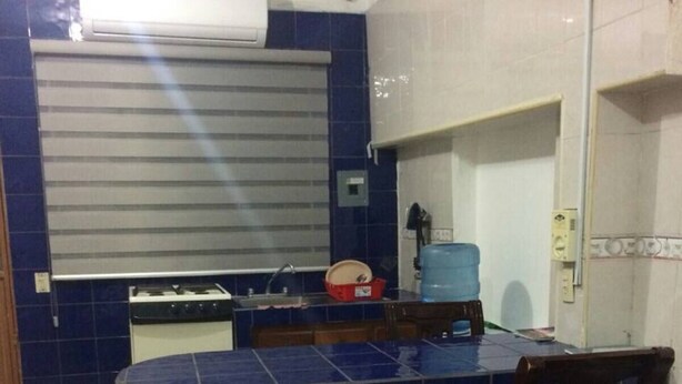 A compact kitchen with a gas stove, a sink, and a blue-tiled counter.