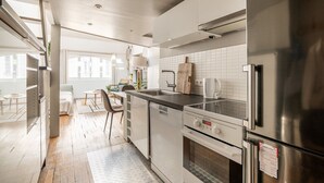 A modern kitchen with a built-in oven, a stainless steel refrigerator, and a coffee maker. - Bright & Chic Duplex with A/C – Heart of Paris 9th (Paris)