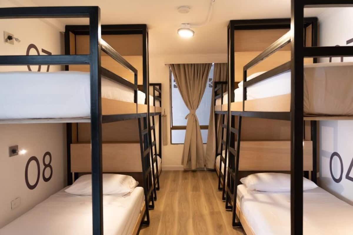 A room with bunk beds, numbered 08 and 04, wooden flooring, and a window with curtains.